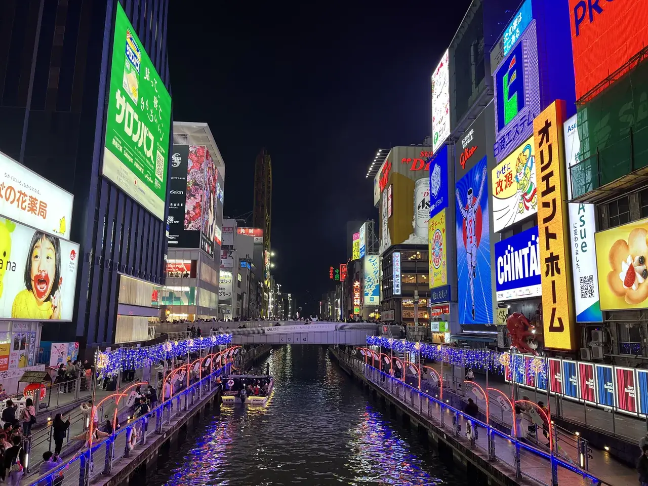 Canal de Dotonbori en Osaka, iluminado de noche y lleno de gente